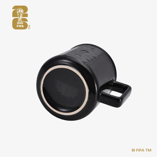 FIFA World Cup 26 black ceramic mug tilted to show tonal We Are 26 emblem and footed base, 12 ounce